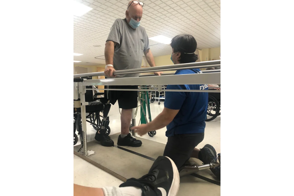 Todd Schaffhauser helping an amputee at the parallel bars